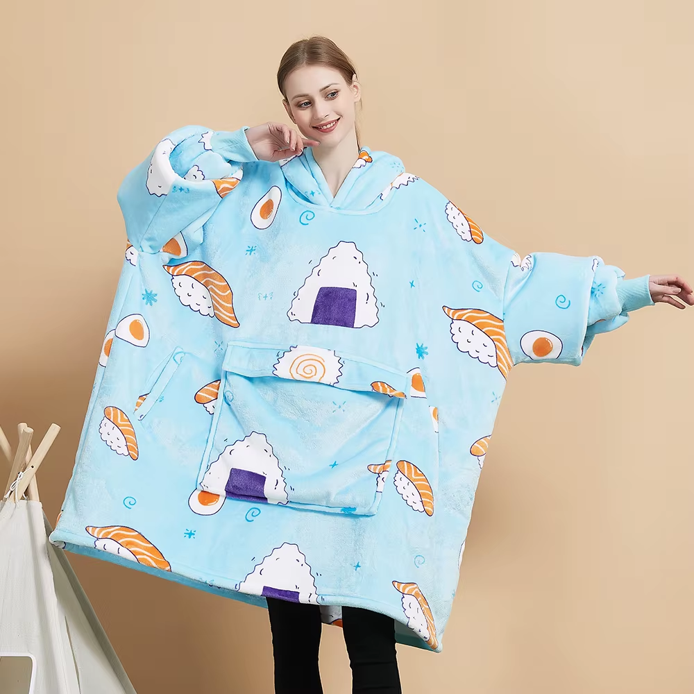 Model wearing the Sushi Roll oversized wearable blanket in powder blue printed with salmon nigiri, onigiri rice balls and eggs, with a giant kangaroo pocket